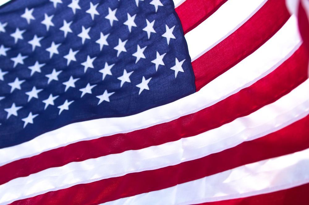 Close-up of an American flag waving, red and white stripes and white stars on blue.