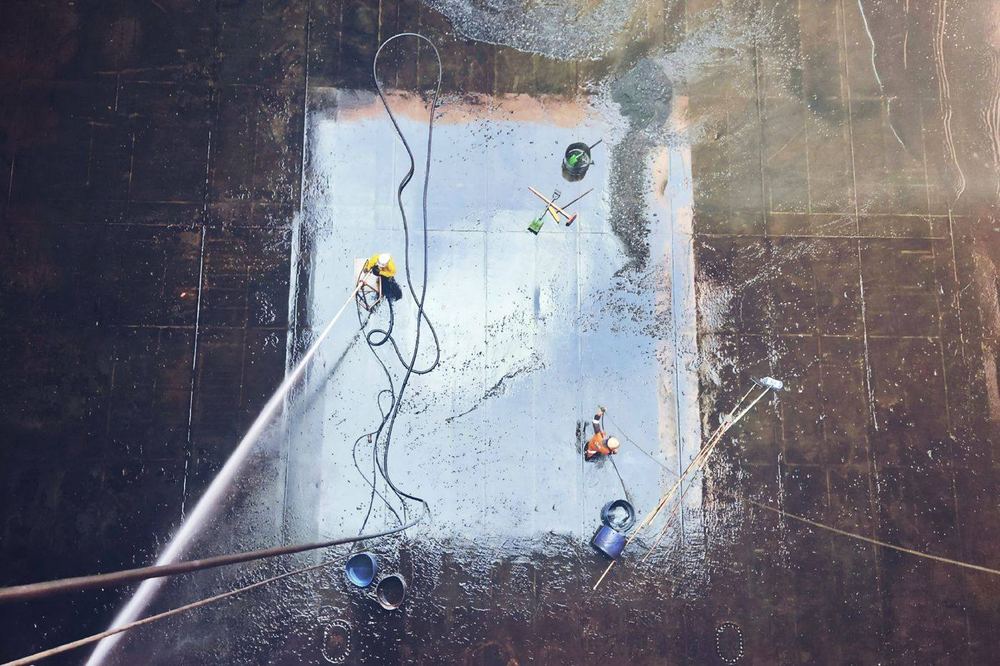Overhead view of workers washing a large dark floor.
